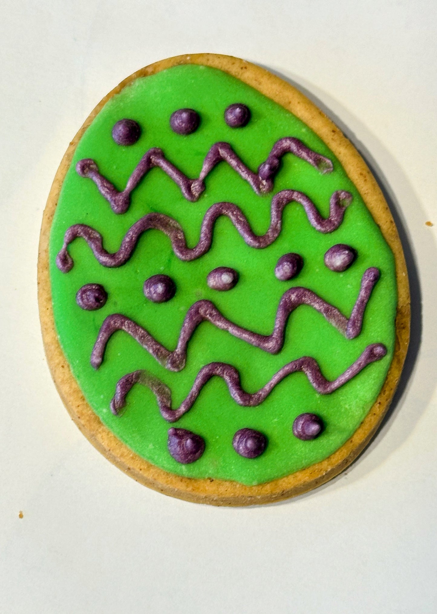 Large Easter egg dog biscuit decorated with green and purple icing