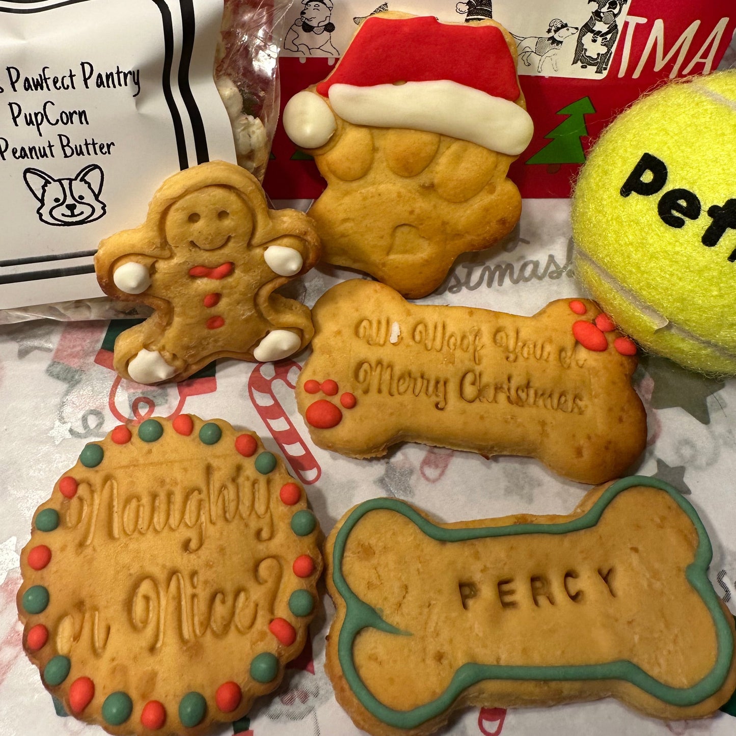 A selection of Christmas dog biscuits, with a packet of pupcorn and tennis ball