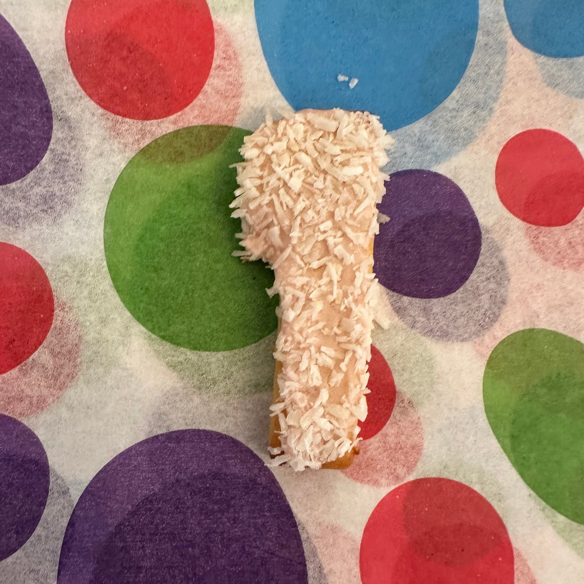 Large coconut-covered number dog biscuit with colourful icing