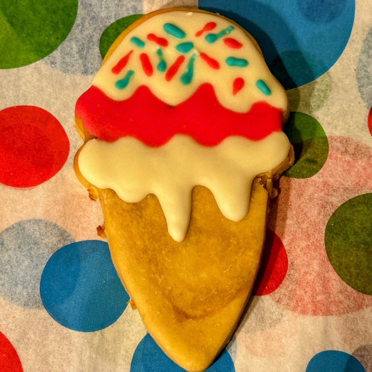 A dog treat shaped like an ice cream cone with a multicolored sprinkle topping