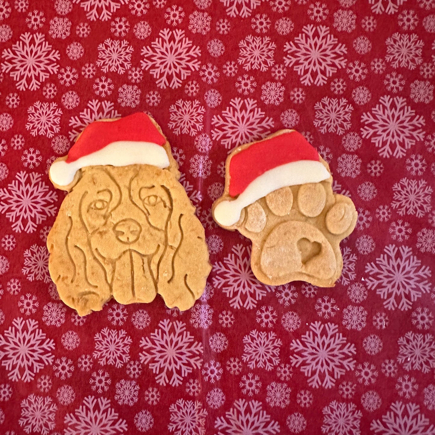 Spaniel shaped dog biscuits with dog face in a Santa hat, and a paw with a santa hat