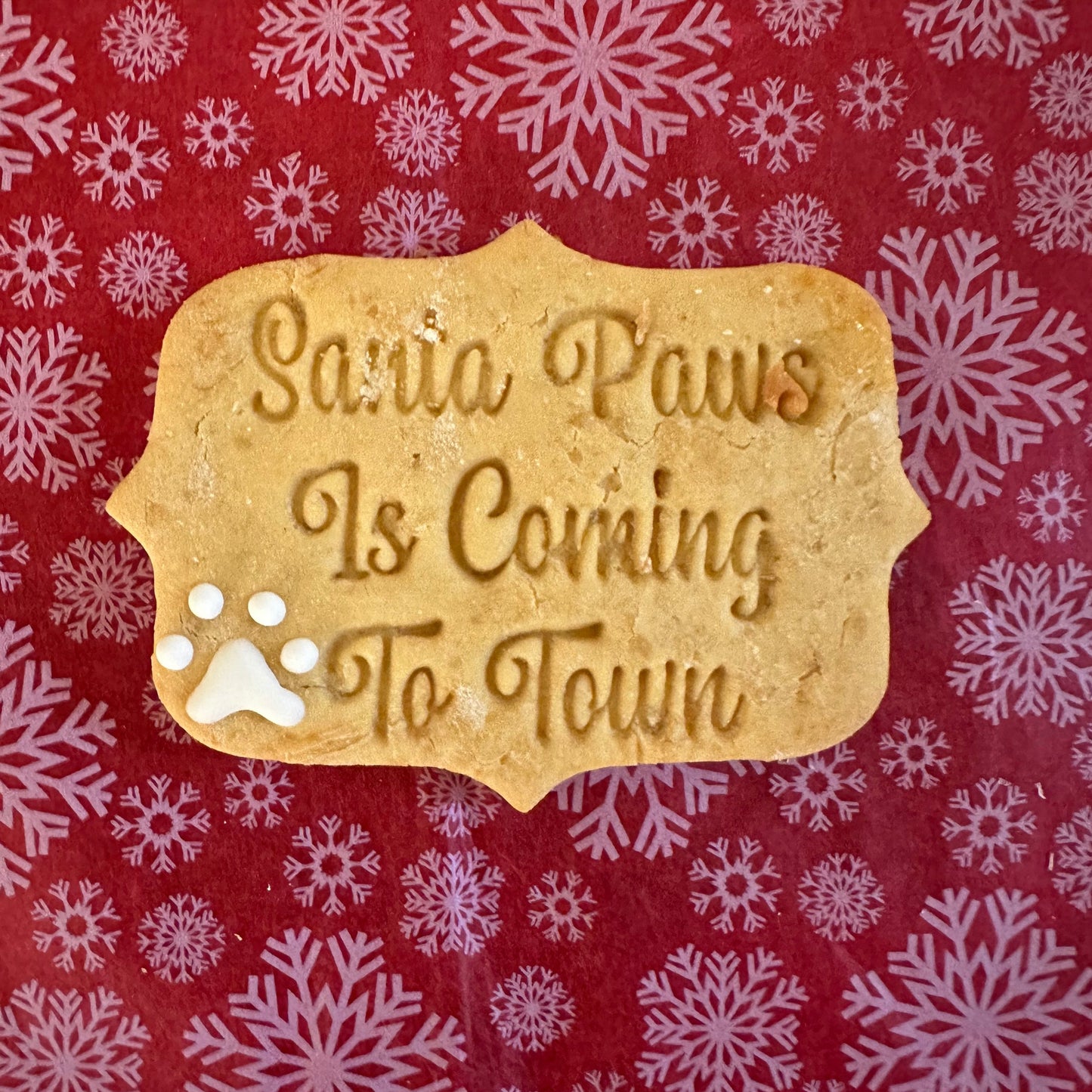 A large, decorative dog treat shaped like a cookie, with 'Santa Paws is Coming to Town' text and a paw print design.
