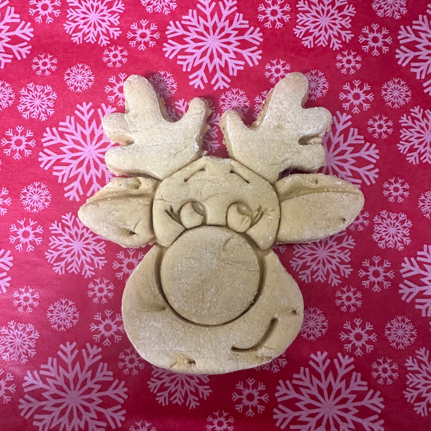 Reindeer cookie cutter on a red background with snowflake patterns