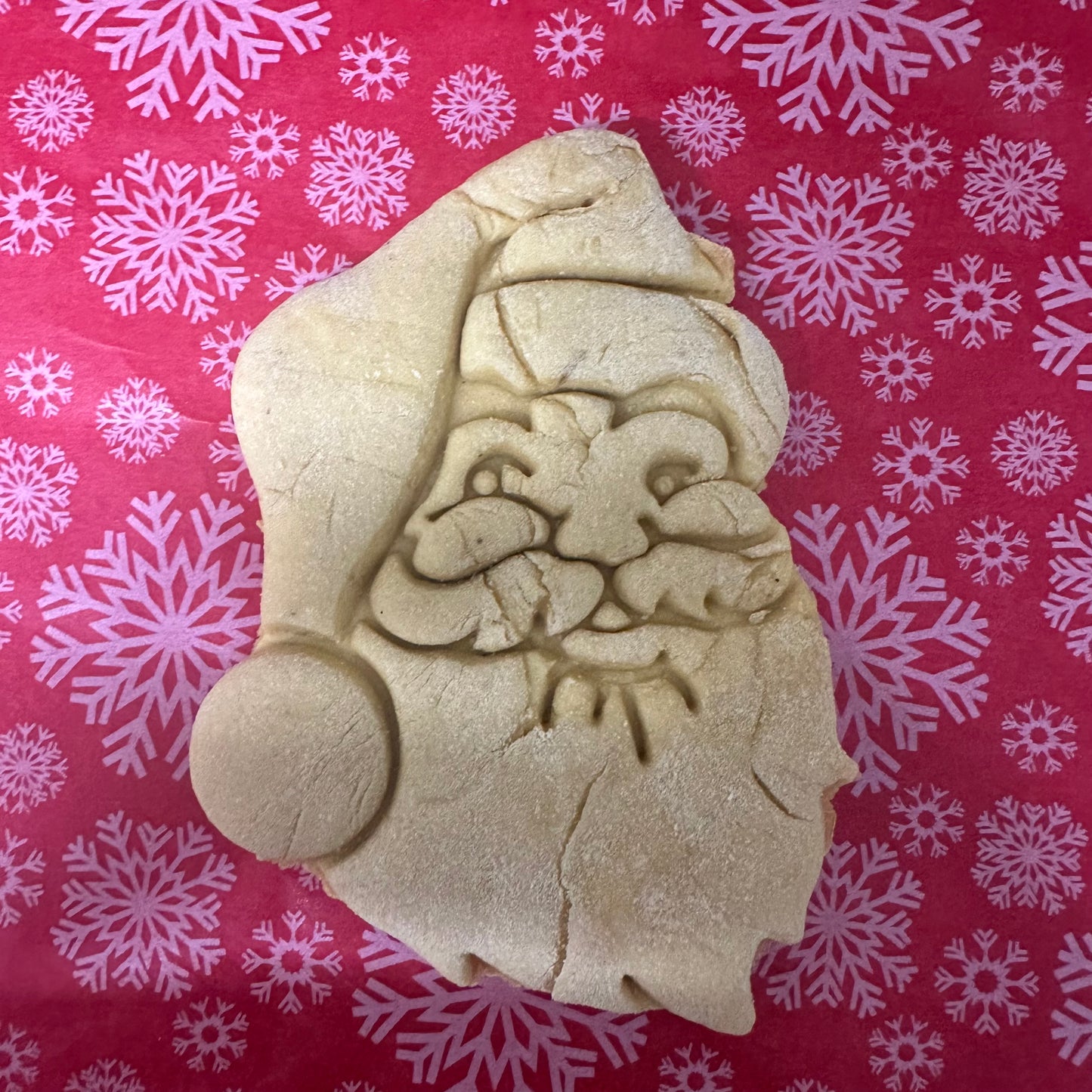 Santa Claus cookie on a red background with snowflake patterns