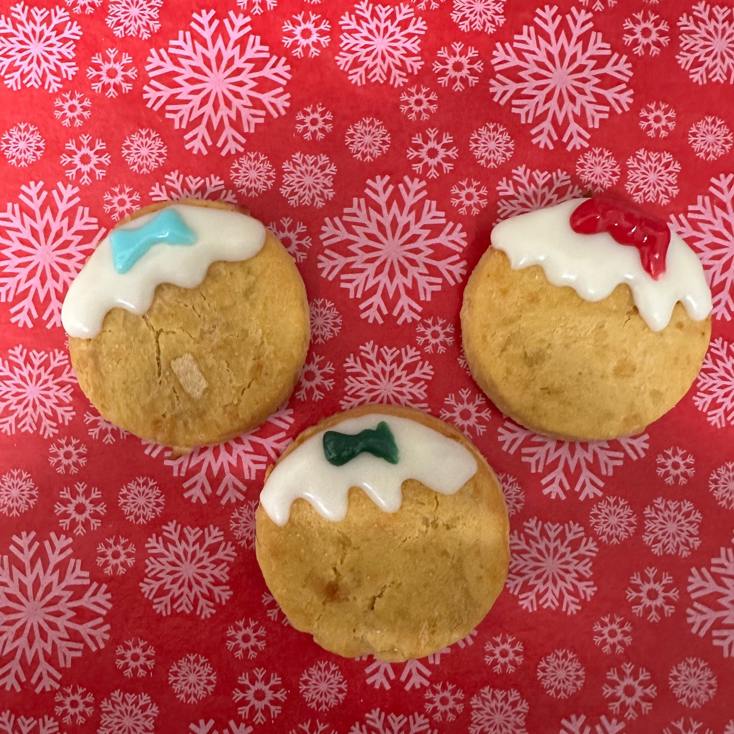 Three cookies with icing on a red background with snowflake patterns