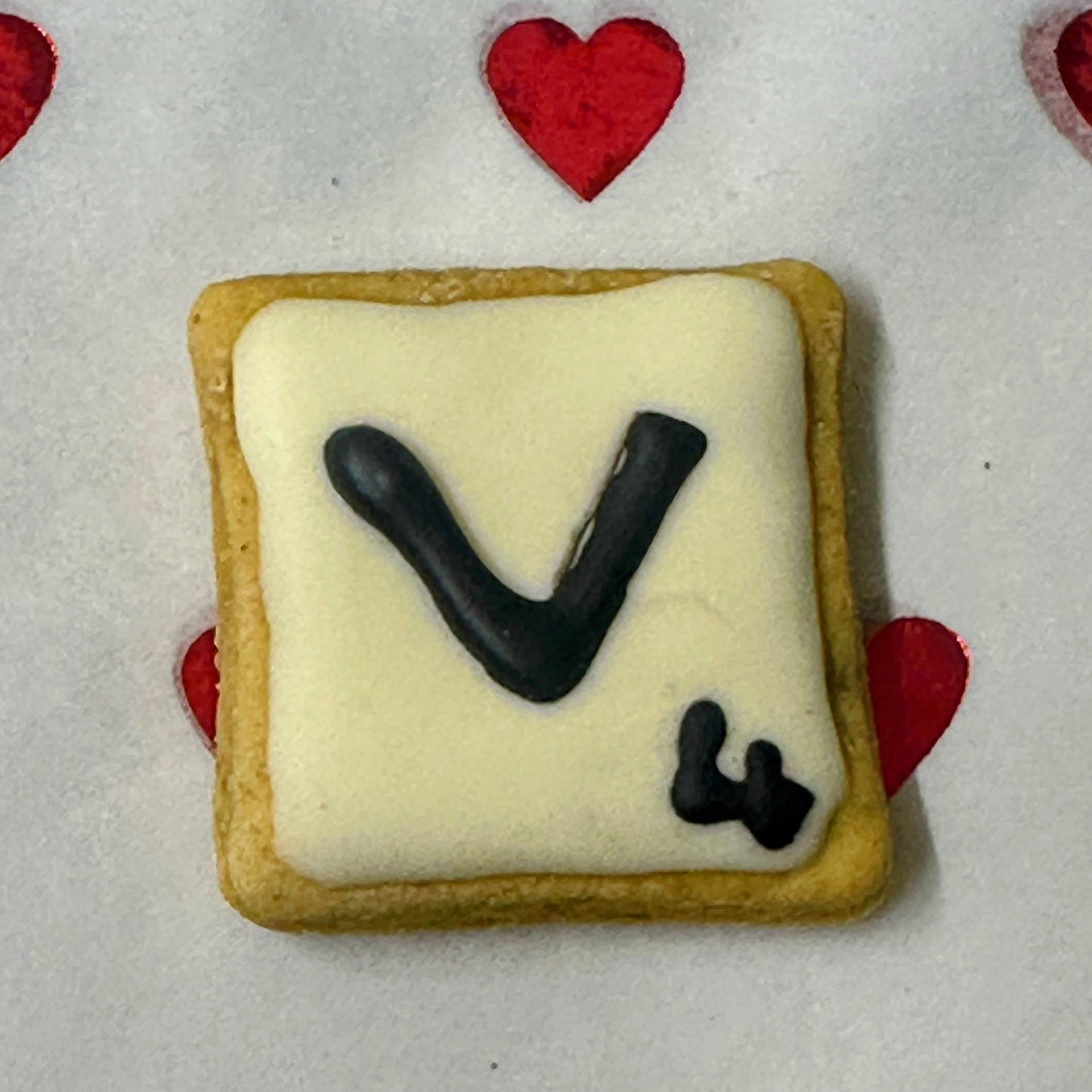 Cookie with letter 'V' on a white background with red hearts