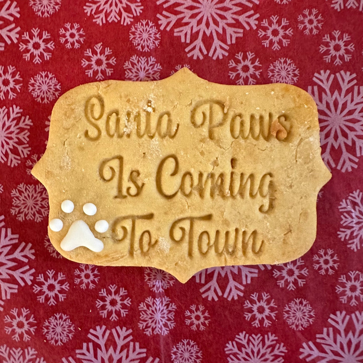 A rectangle shaped dog biscuit with the text "Santa Paws is coming to town"