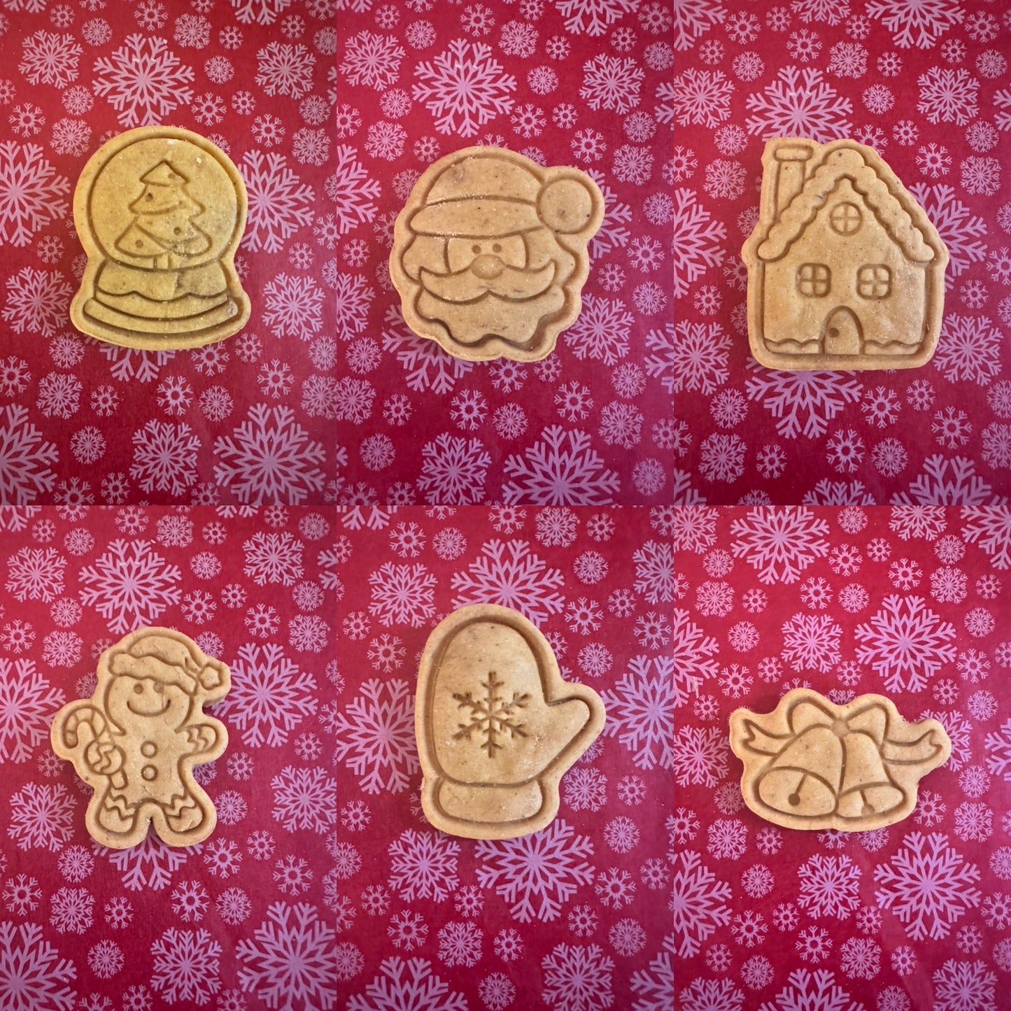 A variety of Christmas-themed dog biscuits arranged on a patterned background, including designs like Santa, reindeer, snowflakes, and festive houses.