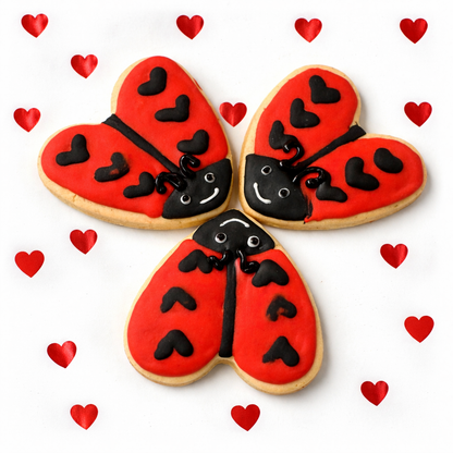 Heart-shaped cookies decorated like ladybugs on a white background with red heart decorations.