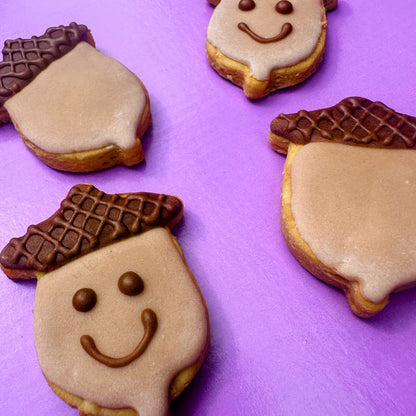 Cookies shaped like acorns with smiling faces on a purple background