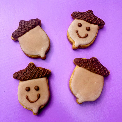 Four cookies shaped like acorns with faces on a purple background