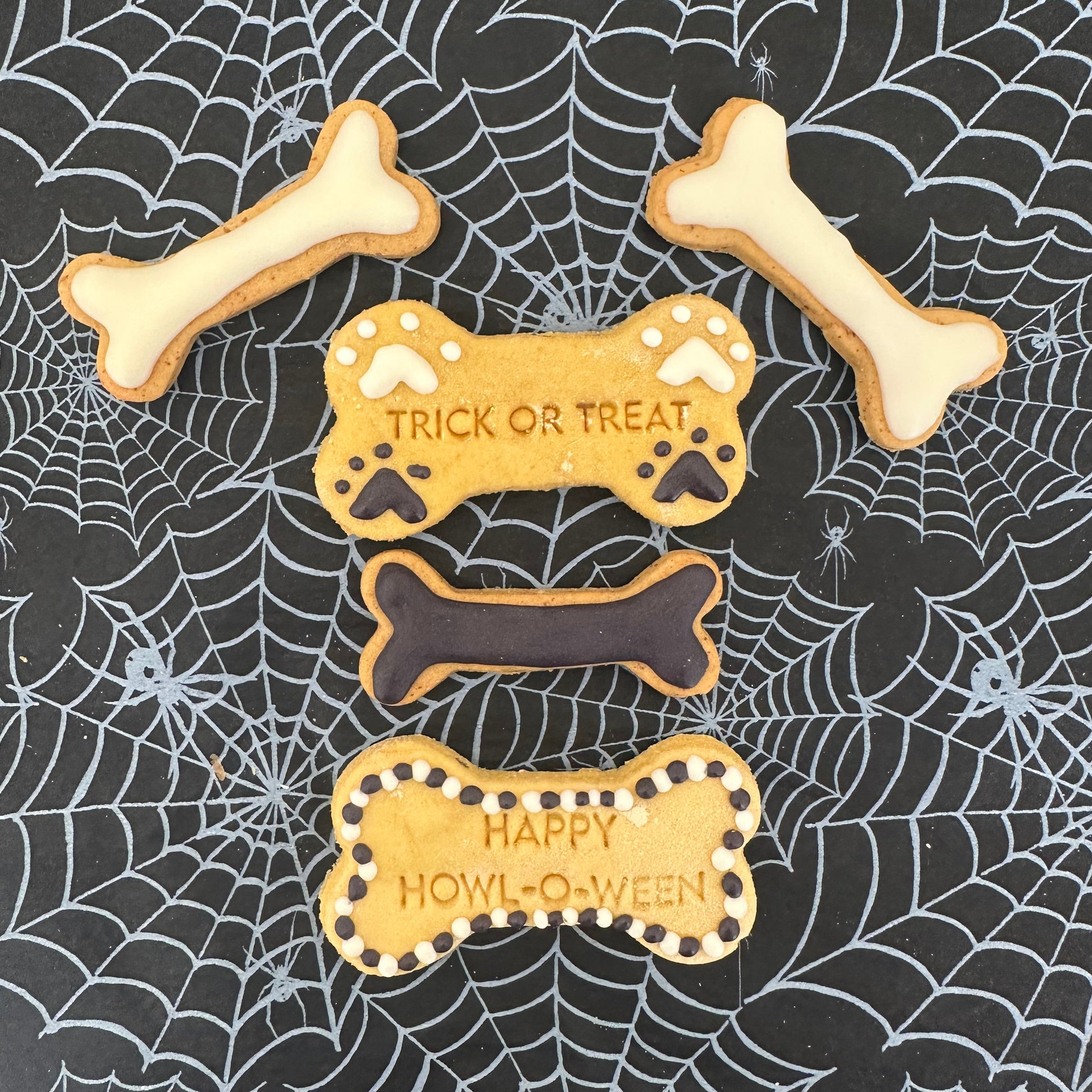 Halloween-themed cookies shaped like bones on a spider web background