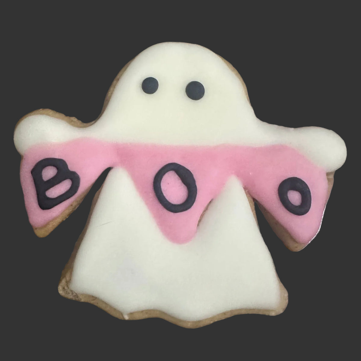 A ghost-shaped  cookie decorated with white icing, a pink banner across the middle, and the word 'BOO' in black icing