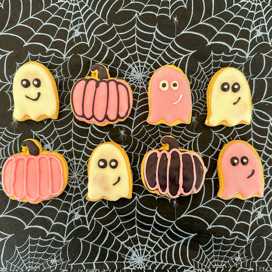 Halloween-themed cookies shaped like ghosts and pumpkins on a spider web background