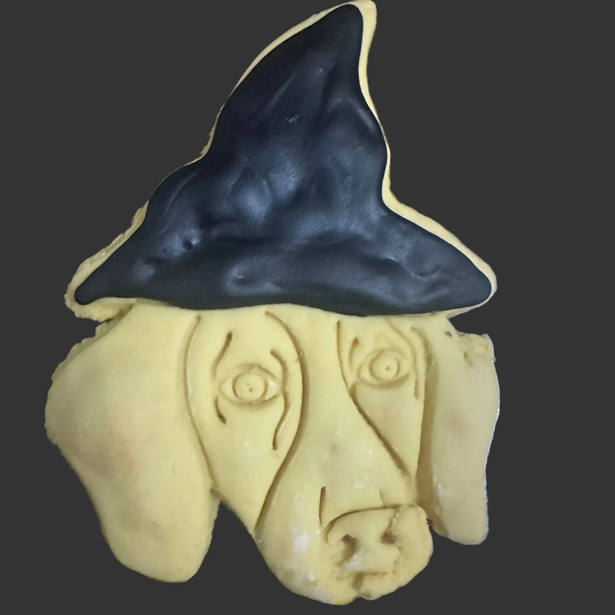 A dog-shaped sugar cookie with a black wizard hat