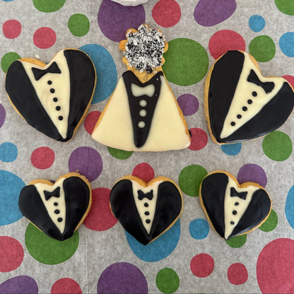 Heart-shaped cookies decorated like tuxedos on a polka dot background