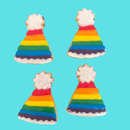 Four rainbow-colored party hats with white frosting on a blue background