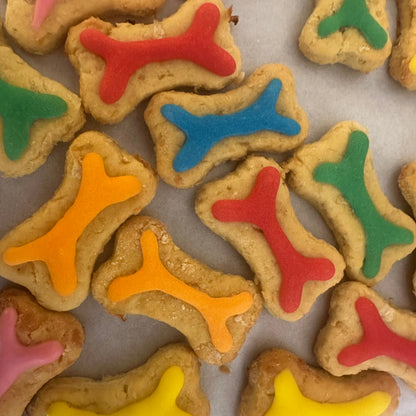 Dog treats shaped like bones with colorful icing on a baking sheet.