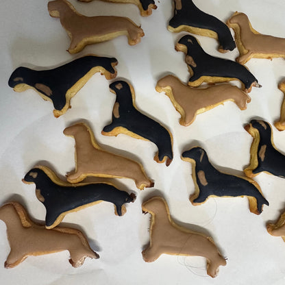 Dachshund-shaped cookies in brown and black on a white surface