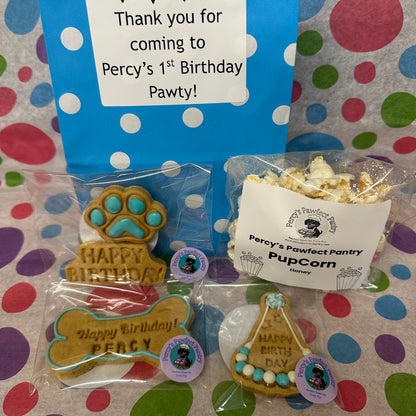 Dog-themed birthday party favors including treats and popcorn on a polka dot background