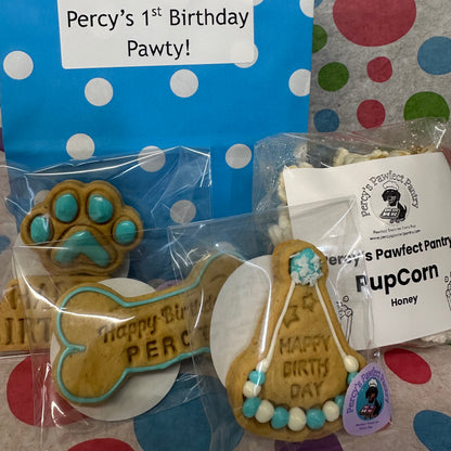 Dog-themed birthday party favors including cookies and popcorn with 'Percy's Pawfect Pantry' branding.