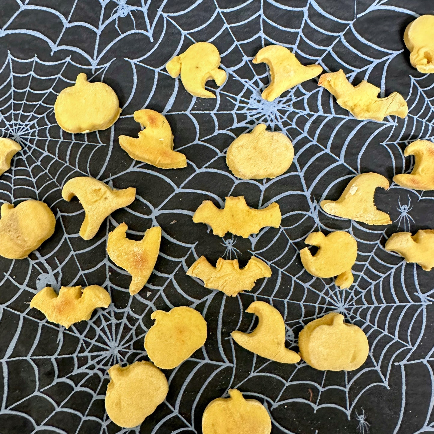 Yellow Halloween-themed cookies on a black spider web background