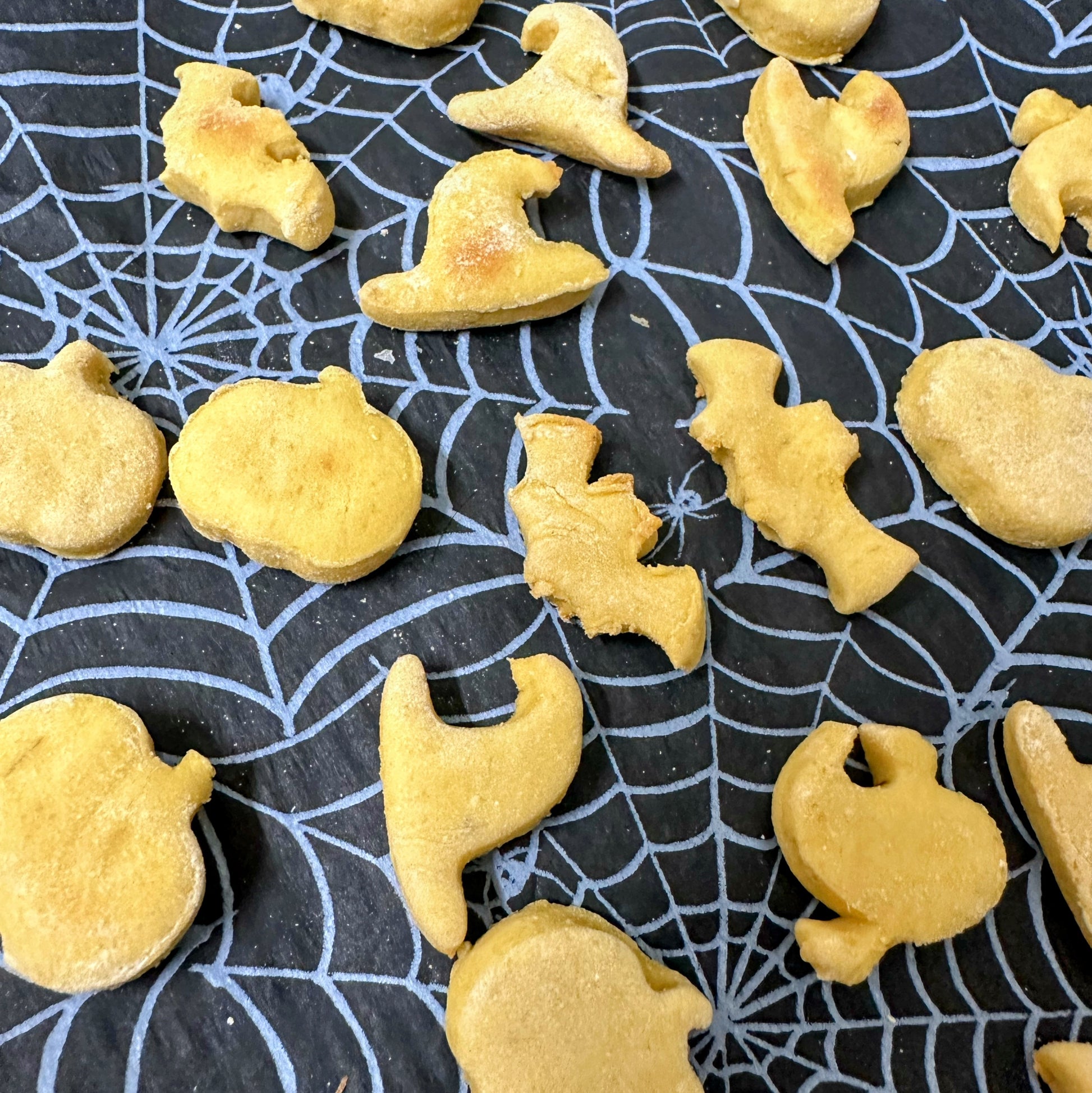 Yellow Halloween-shaped cookies on a black spider web background
