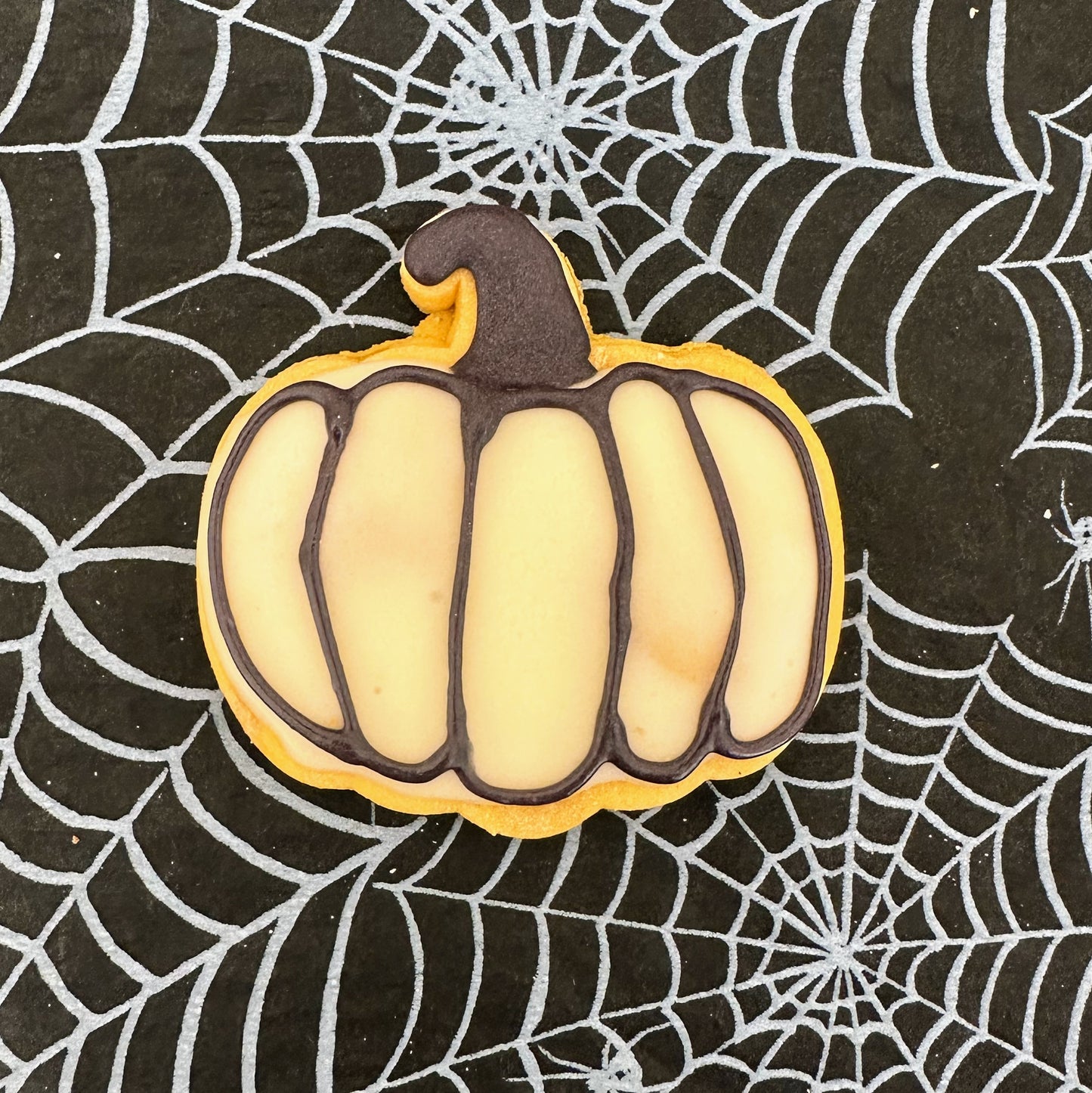 Pumpkin-shaped cookie on a spider web background