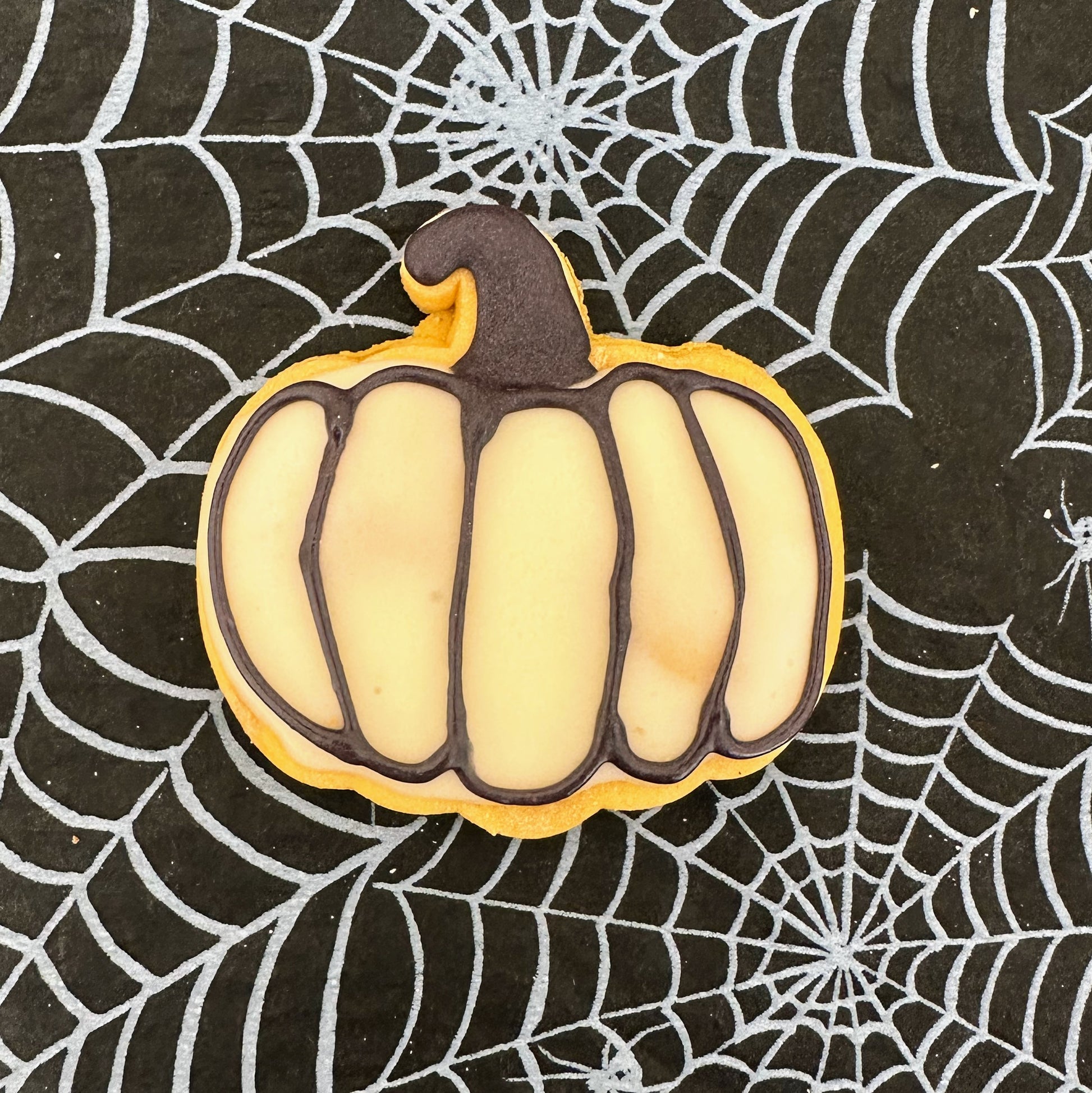 Pumpkin-shaped cookie on a spider web background