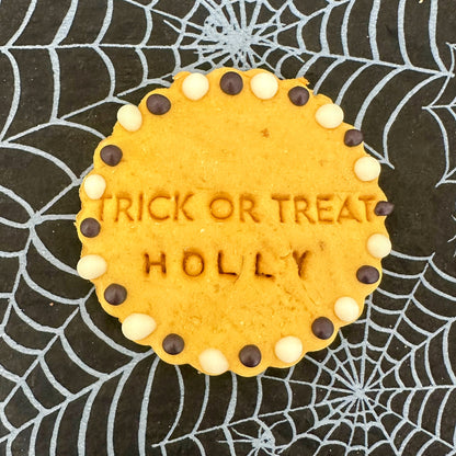 Cookie with 'TRICK OR TREAT HOLLY' text on a spider web background