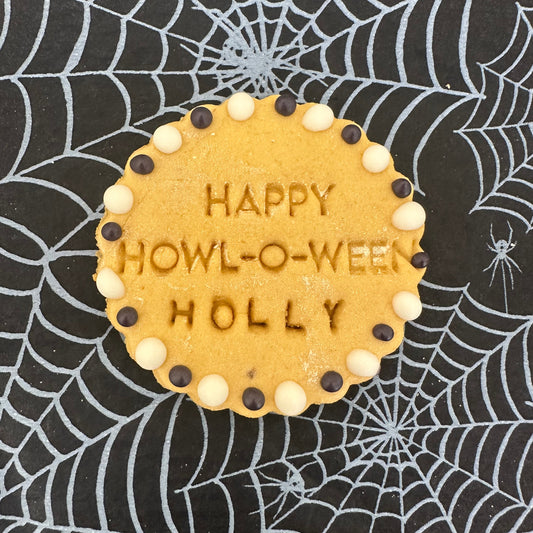 Cookie with 'Happy Howl-o-Ween Holly' text on a spider web background