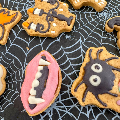 Halloween-themed cookies with spider and mouth designs on a spider web background