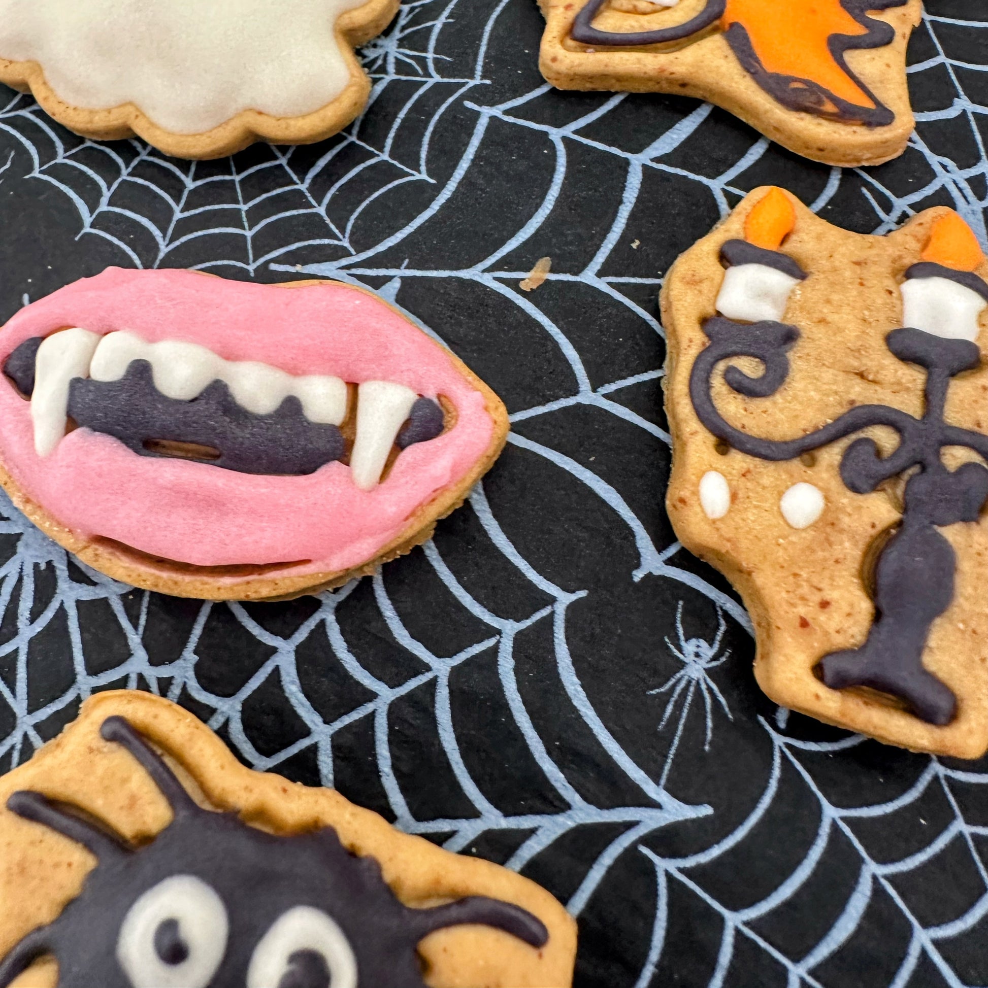 Halloween-themed cookies with decorative icing on a black spider web background