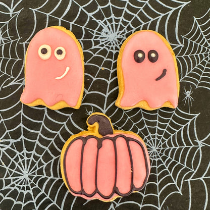 Halloween-themed cookies shaped like ghosts and a pumpkin on a spider web background
