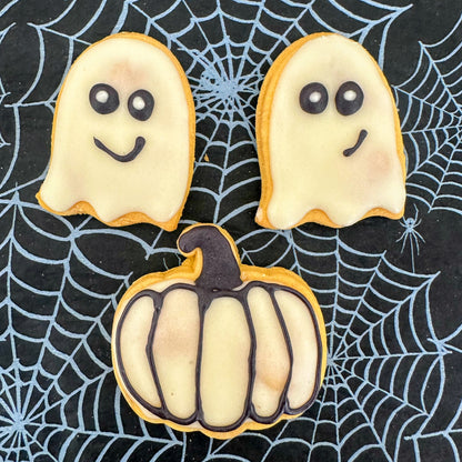 Halloween-themed cookies shaped like ghosts and a pumpkin on a spider web background
