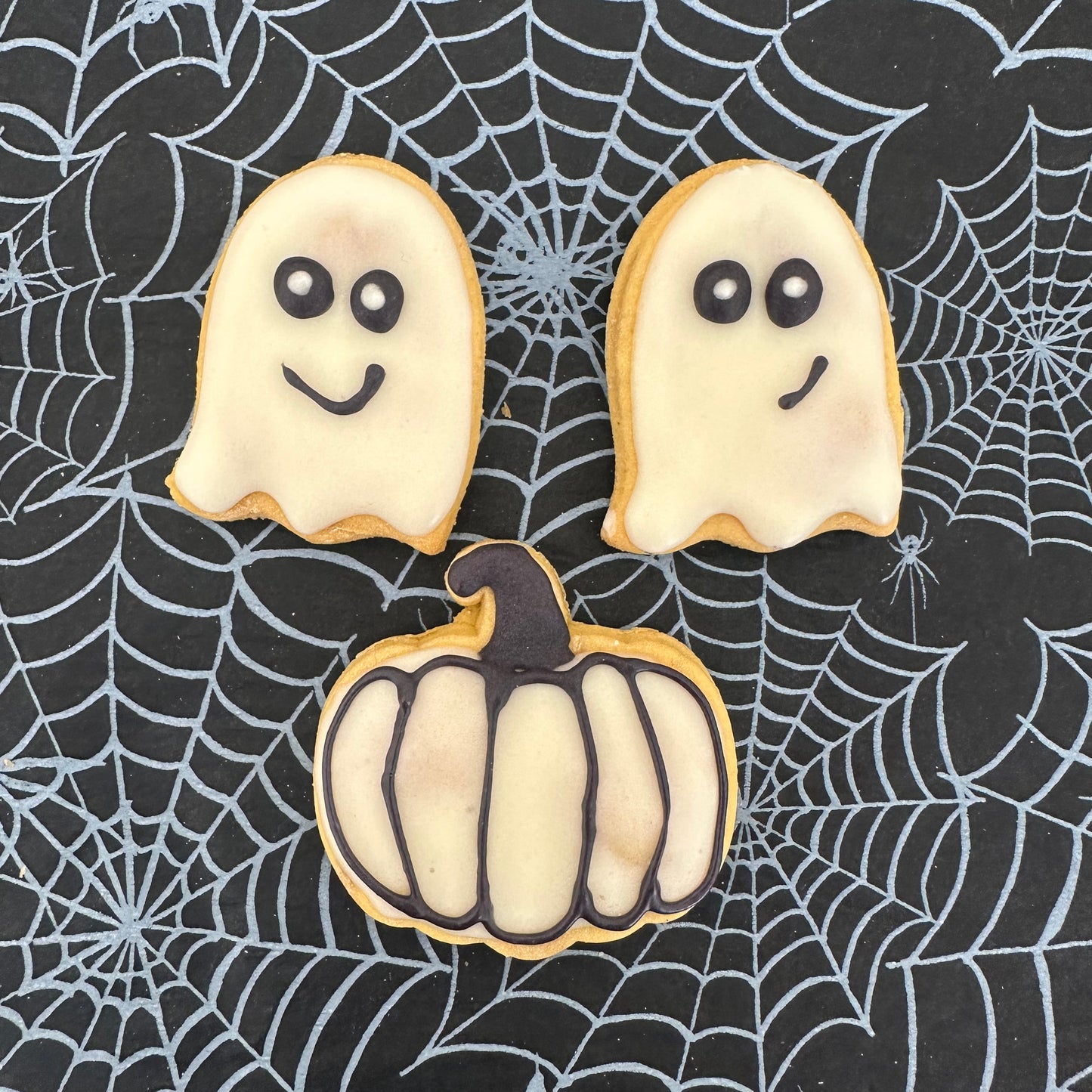 Halloween-themed cookies on a spider web background