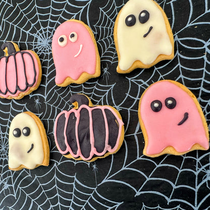 Halloween-themed cookies shaped like ghosts and pumpkins on a spider web background