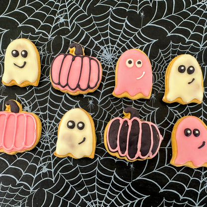 Halloween-themed cookies shaped like ghosts and pumpkins on a spider web background