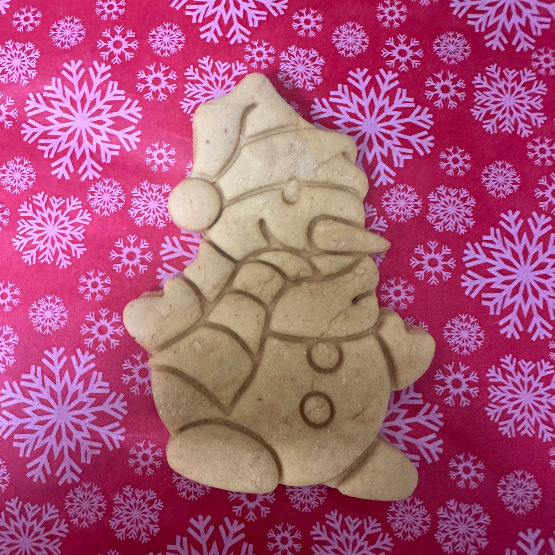 Decorative cookie of a snowman on a red background with white snowflakes