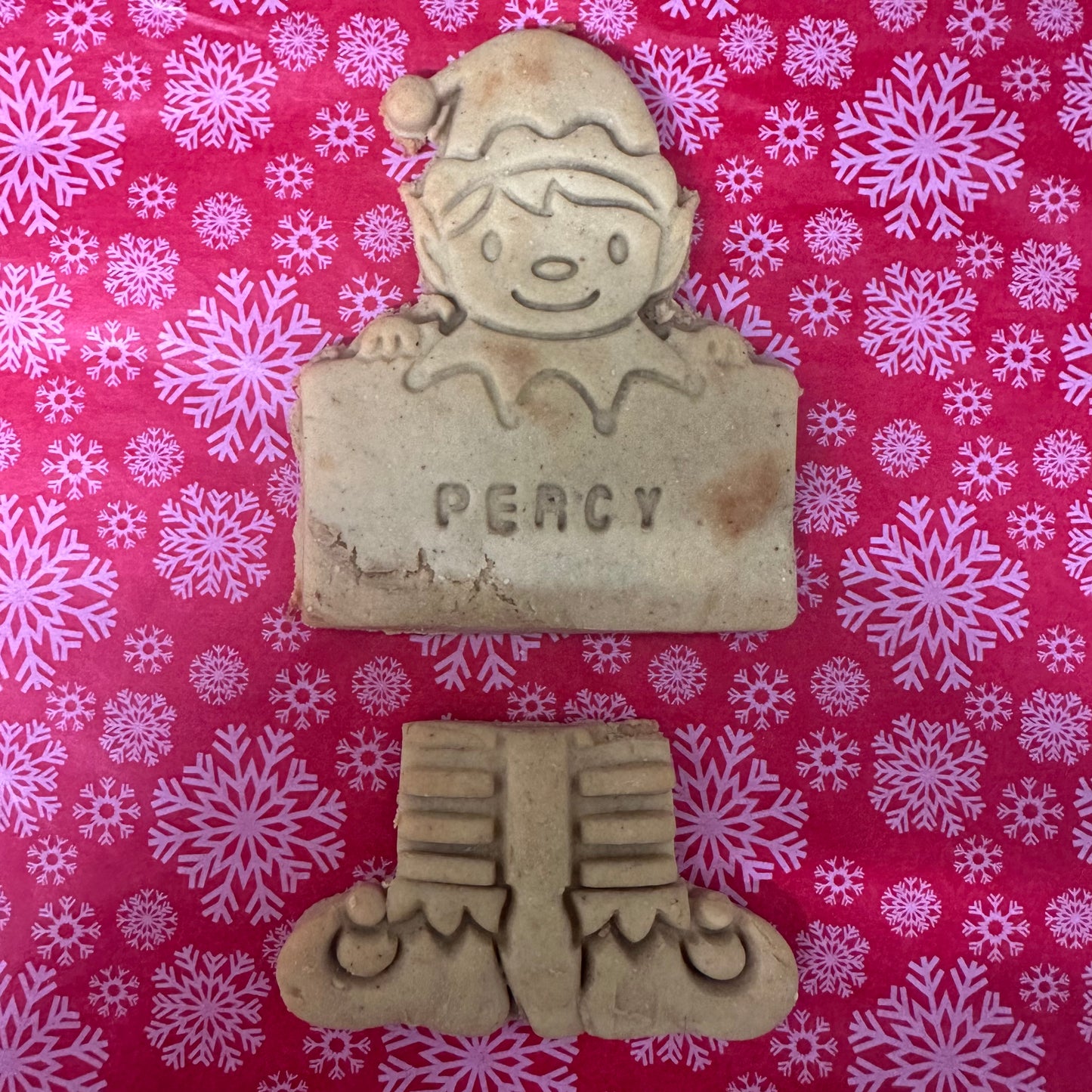 Cookie of a elf named Percy on a red background with snowflake patterns