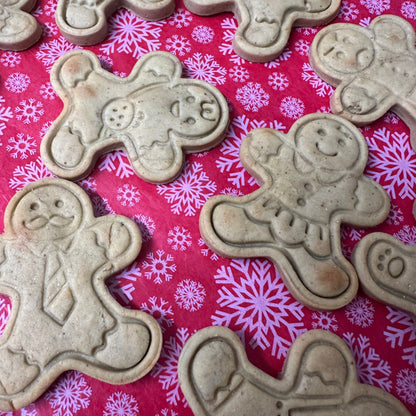 Gingerbread men cookie cutters on a pink background with snowflake patterns