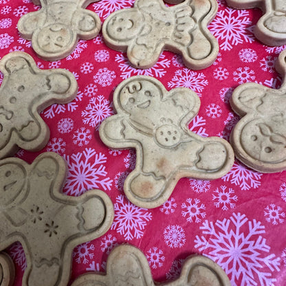 Biscuit cutouts shaped of gingerbread me on a red surface with snowflake pattern