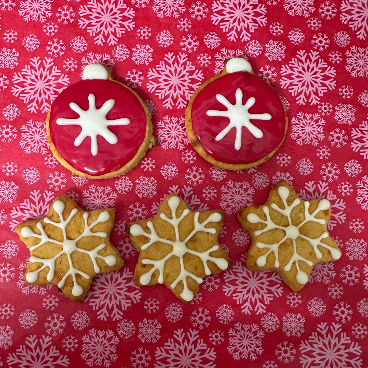 Decorative cookies with snowflake designs on a red background with snowflake pattern