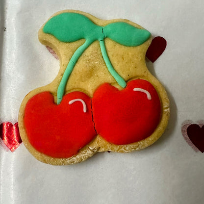 Decorative cookie shaped like cherries with red icing on a white background