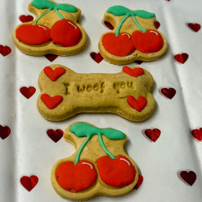 Dog treats shaped like bones and cherries with 'I woof you' text on a heart-patterned background.