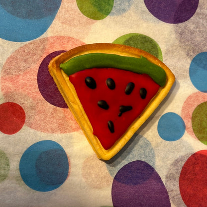 Colorful cookie shaped like a watermelon slice on a polka dot background