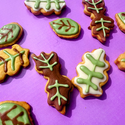 Leaf-shaped cookies with green and brown icing on a purple background