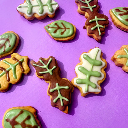 Leaf-shaped cookies with green and brown icing on a purple background