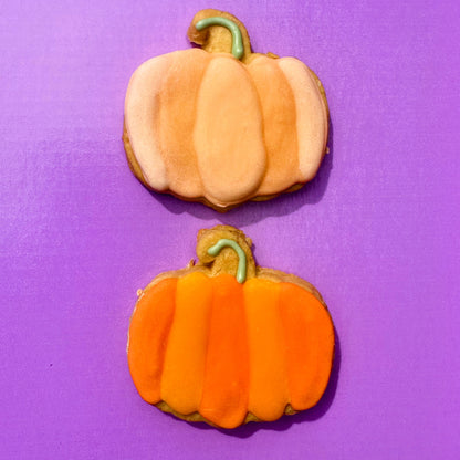 Two pumpkin-shaped cookies on a purple background