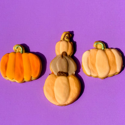 Three pumpkin-shaped cookies on a purple background